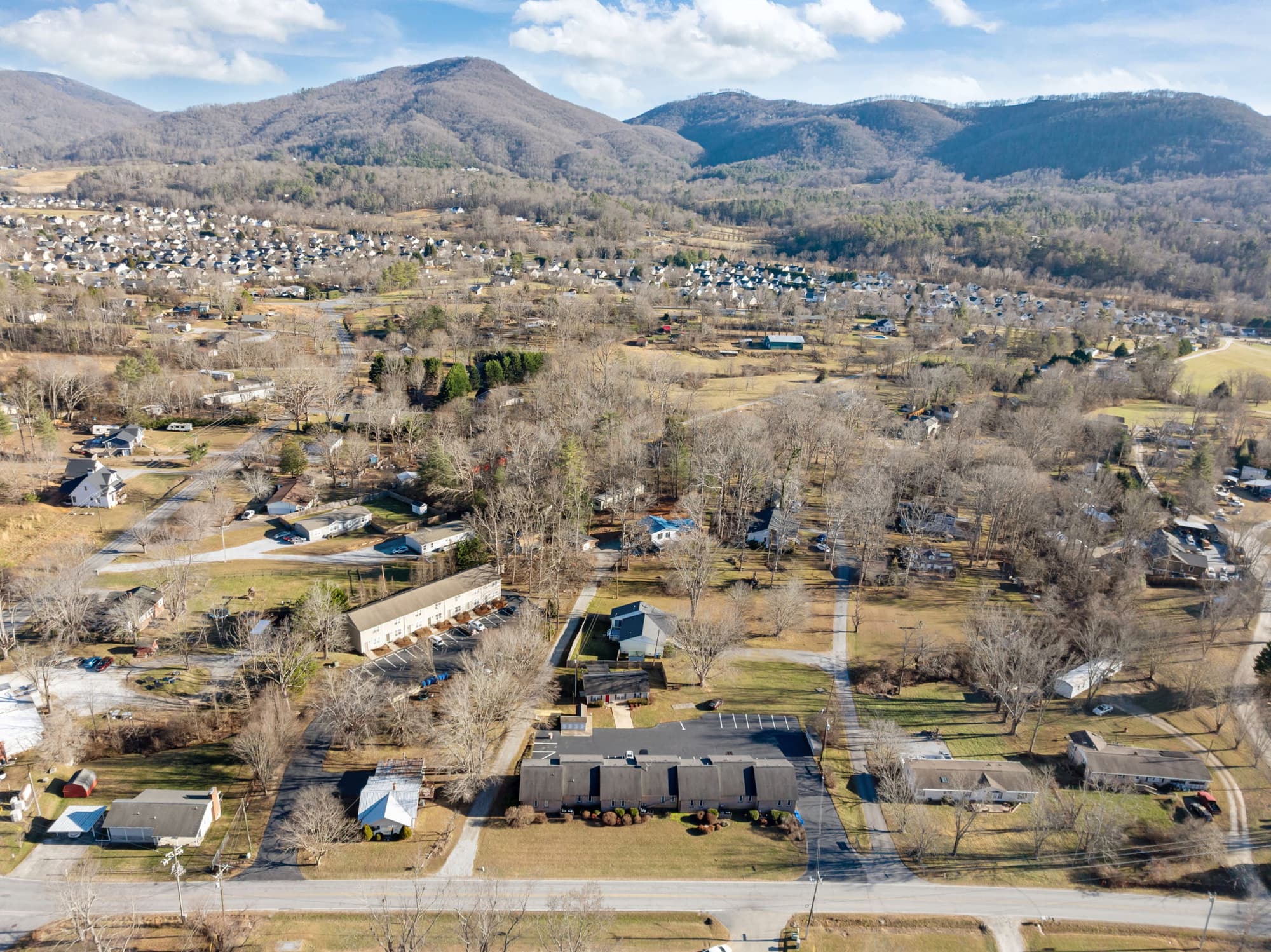 Aerial view of the full Fletcher Townhomes community, all four buildings, with the Blue Ridge Mountains behind